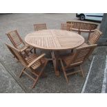 A 5ft round teak garden table and a set of six folding chairs