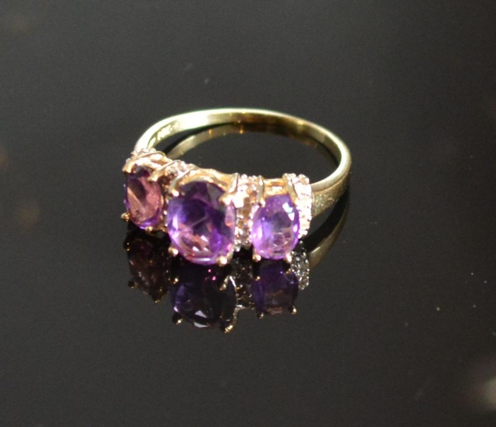 A Yellow Gold Amethyst And Diamond Set Ring with three oval amethyst interspaced with diamonds