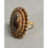 A 14ct. Gold Garnet Set Cluster Ring Of Oval Form With Tiered Rows Of Garnets