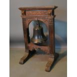 An Early Patinated Bronze Bell Mounted Within An 18th Century Oak Stand, the outswept legs with