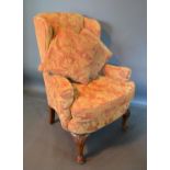 A Queen Anne Style Upholstered Wingback Armchair, with shell carved cabriole legs and pad feet