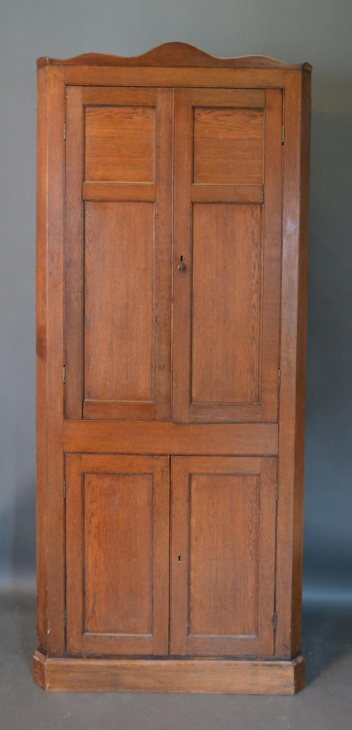 A 19th Century Oak Standing Corner Cabinet, the moulded top above four panel doors enclosing