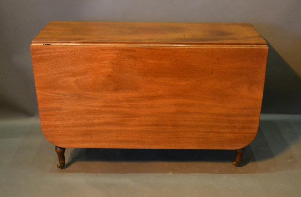 An Early 19th Century Mahogany Drop Flap Dining Table, with ring turned tapering legs, brass caps