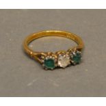 An 18ct. Gold Diamond And Emerald Three Stone Ring, set with a central diamond flanked by emeralds