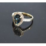 A Yellow Gold Blue Topaz And Diamond Ring set with a teardrop blue topaz surrounded by diamonds