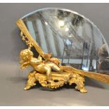 A Gilt Bronze Table Mirror in the form of Putti with a Fan upon shaped scroll feet, 25 cms tall