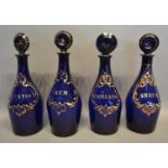 A Set Of Four Early 19th Century Blue Glass Decanters, all highlighted with gilt, Brandy, Rum,