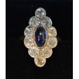 A Yellow Gold Diamond and Sapphire Dress Ring with a central oval cabochon sapphire surrounded by