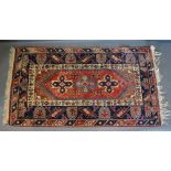 A North West Persian Woollen Rug with a central medallion within an allover design upon a red,