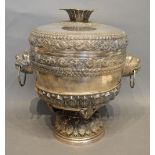 An Indian White Metal Large Covered Vase on Stand, the shaped cover above mask ring handles and