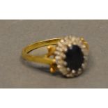 An 18 Carat Yellow Gold Sapphire and Diamond Cluster Ring set with central oval sapphire
