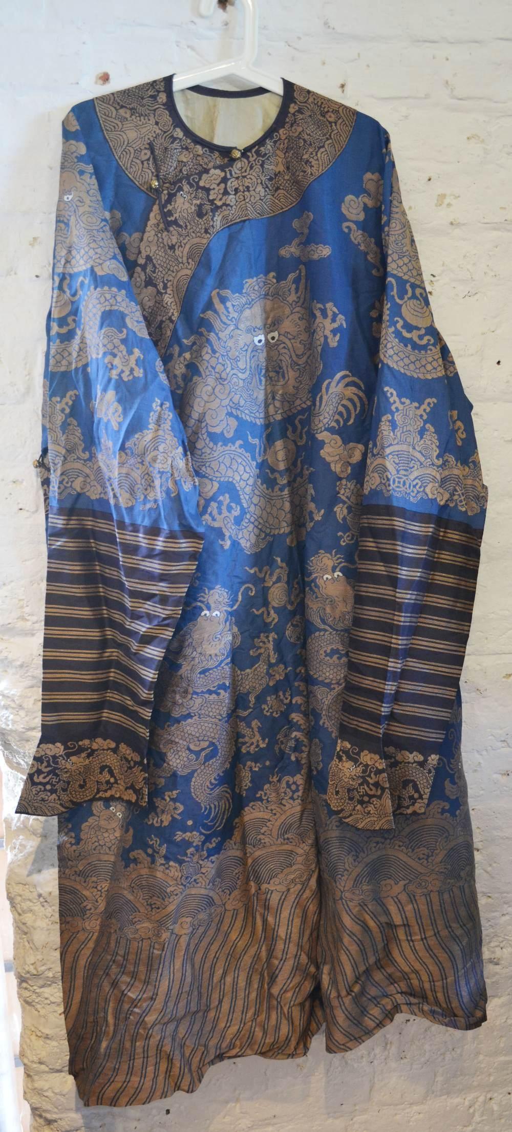 A Chinese Embroidered Kimono decorated with serpents amongst waves in gold thread upon a blue ground