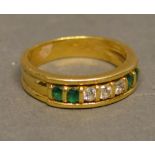 An 18 Carat Yellow Gold Diamond and Emerald Set Ring set with three central diamonds flanked by four