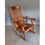 A Chinese Hardwood Rocking Chair with a shaped spindle back above a panel seat raised upon square