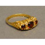 An 18 Carat yellow Gold Garnet and Diamond Ring set with three graduated garnets interpersed with