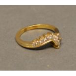 A 14 Carat Yellow Gold and Diamond Set Ring set with seven diamonds in an unusual curved form