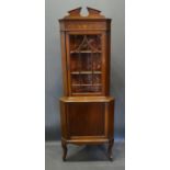 An Edwardian Mahogany Marquetry Inlaid Standing Corner Cabinet with a glazed door enclosing shelves,