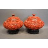 A Pair of Chinese Red Cinnabar Covered Canisters, each with a hardwood stand, 20 cms diameter, 19