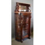 An Early 20th Century Mahogany Display Cabinet, the mirrored top with carved heads above a rouge