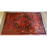 A North West Persian Woollen Rug with a central medallion within an allover design upon a red and