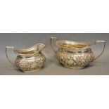 A Birmingham Silver Two Handled Sucrier with embossed decoration, together with a matching cream