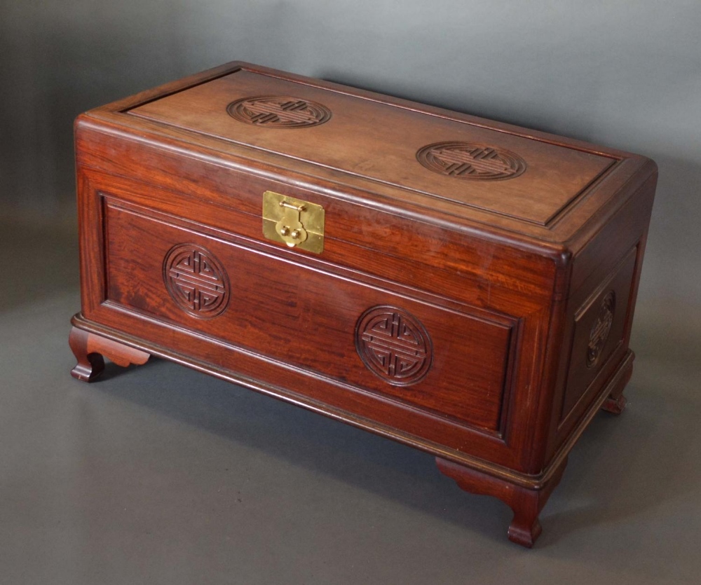 A Chinese Hardwood Chest with a hinged top above a carved panelled front raised upon low shaped