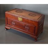 A Chinese Hardwood Chest with a hinged top above a carved panelled front raised upon low shaped