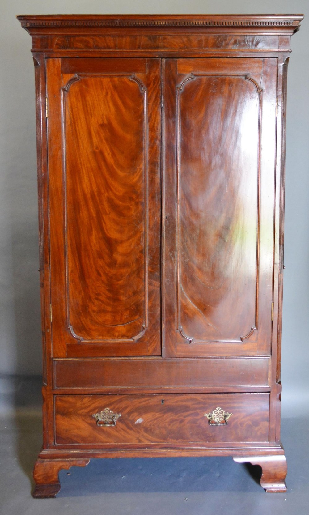 An Early 19th Century Mahogany Hall Cupboard, the moulded cornice above two doors enclosing a