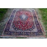 A North West Persian Style Woollen Carpet with a central medallion within an allover design upon a