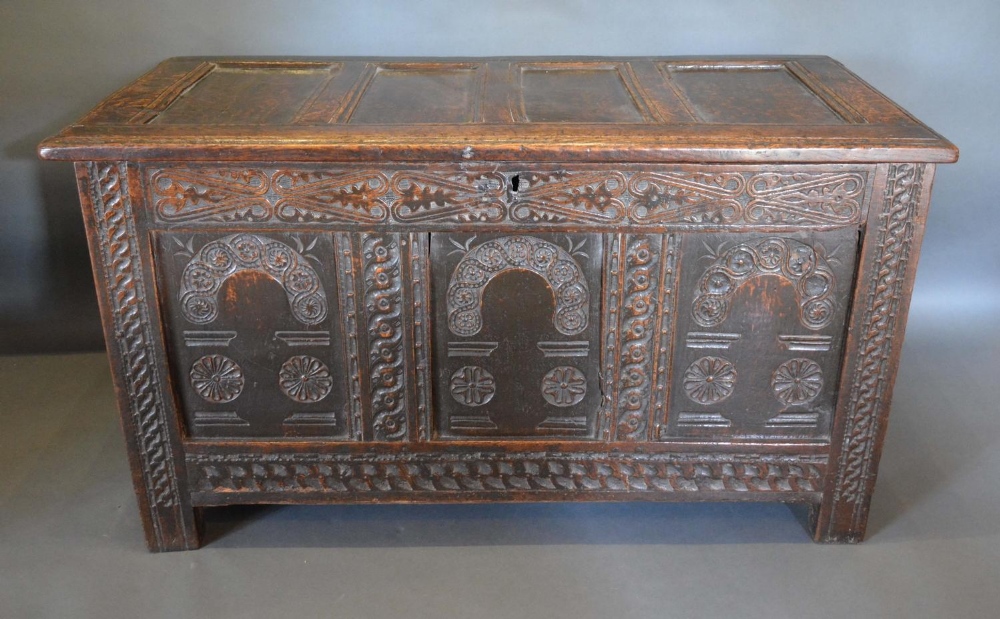 An 18th Century Oak Coffer, the hinged top above a three panelled Arcadian front flanked by