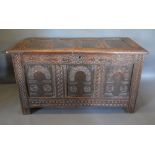 An 18th Century Oak Coffer, the hinged top above a three panelled Arcadian front flanked by