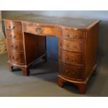 A Reproduction Mahogany Serpentine Twin Pedestal Desk, the tooled leather inset top above nine