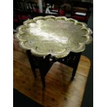 EASTERN METALWARE, late 19th Century brass scalloped edge tray on folding base engraved with