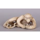 A FINE QUALITY JAPANESE MEIJI PERIOD IVORY OKIMONO OF A MONKEY, reclining and examining some