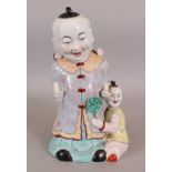 A 20TH CENTURY CHINESE PORCELAIN FIGURE OF A STANDING MAN & HIS TWO SONS, 12.25in high.