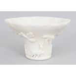 A CHINESE KANGXI PERIOD BLANC-DE-CHINE PORCELAIN LIBATION BOWL, the sides moulded in relief with a