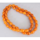 AN AMBER-LIKE BUTTERSCOTCH EGG YOLK NECKLACE, weighing approx. 100gm, composed of oval beads, approx