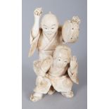 A JAPANESE MEIJI PERIOD IVORY OKIMONO OF A STREET PERFORMER, holding a hand drum and in the