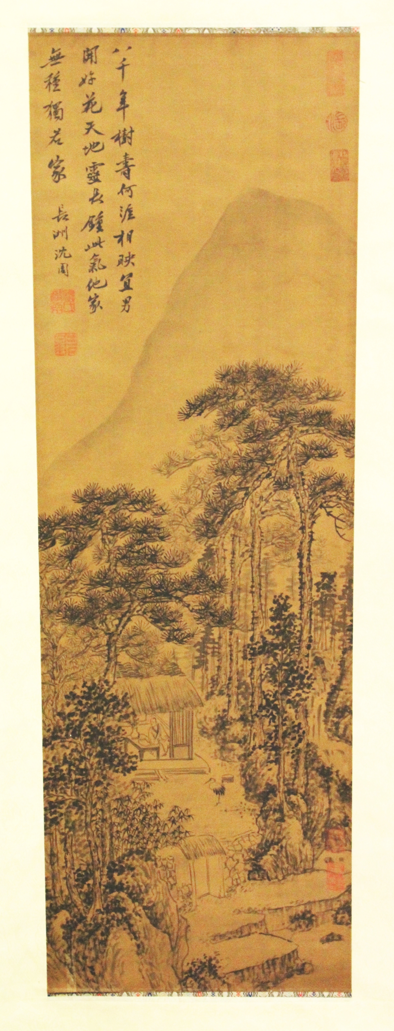 ANOTHER CHINESE HANGING SILK SCROLL PICTURE, depicting a hut beneath pine and before a towering