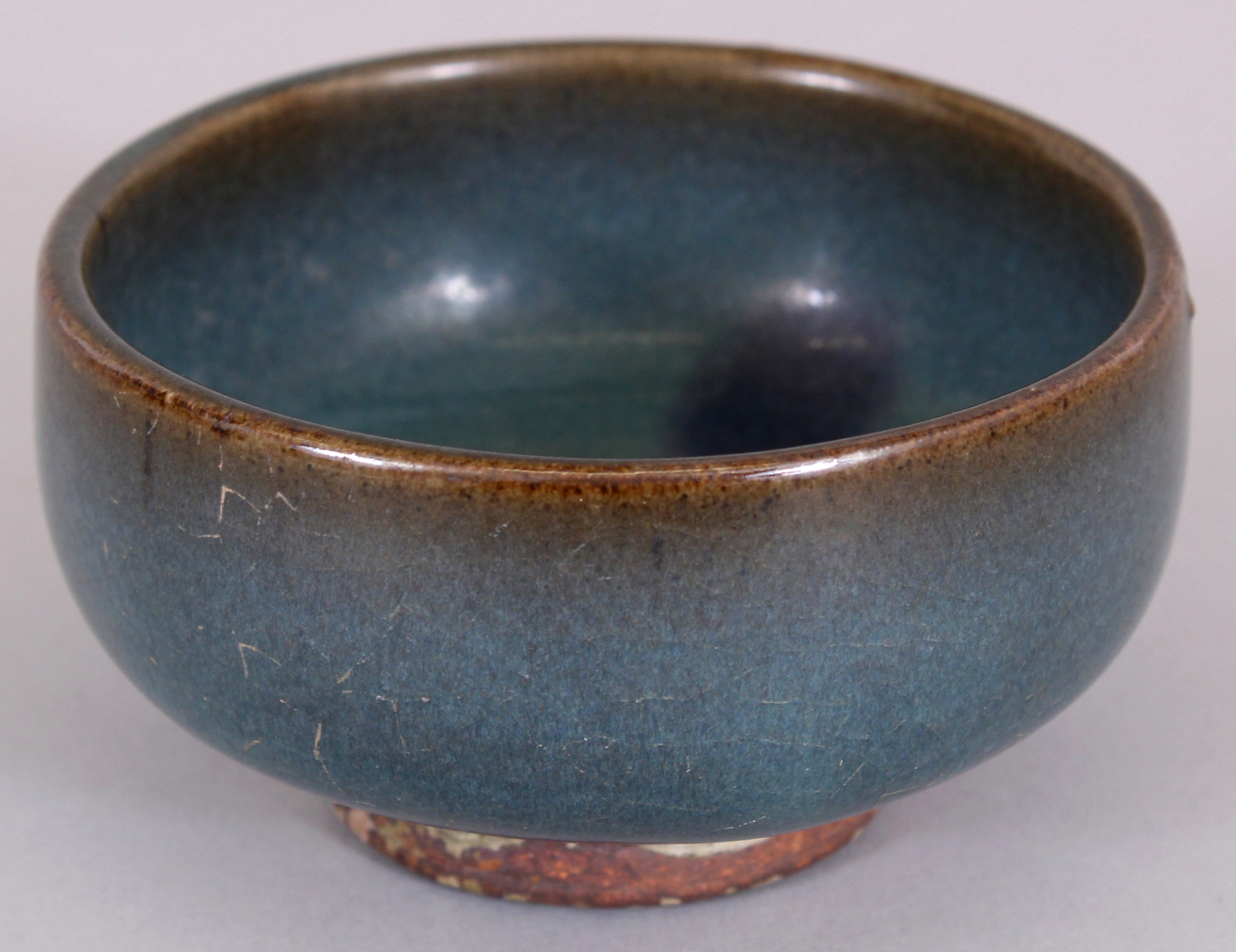 A CHINESE JUN WARE PURPLE SPLASH STONEWARE TEA BOWL, possibly Ming Dynasty, the unglazed base with