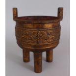 AN UNUSUAL LARGE CHINESE GILT IRON TRIPOD CENSER, Ming Dynasty or later, the sides cast with archaic