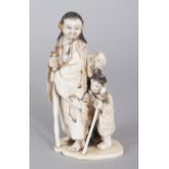 A JAPANESE MEIJI PERIOD IVORY OKIMONO OF A MAN STANDING & HOLDING A STAFF, in the company of his