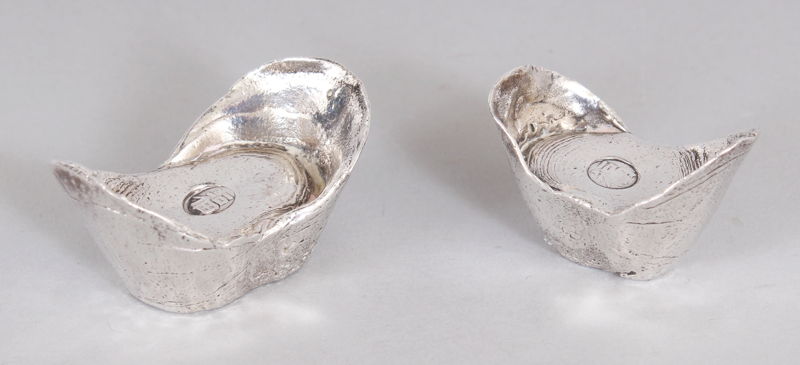 TWO 20TH CENTURY CHINESE SILVER METAL INGOTS, weighing approx. 110gm & 73gm, each interior with an