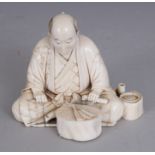 A GOOD QUALITY SIGNED JAPANESE MEIJI PERIOD IVORY OKIMONO OF A SEATED MAN, observing his fan laid on