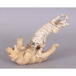 A JAPANESE MEIJI PERIOD IVORY OKIMONO OF A TIGER ATTACKING A BEAR, the details naturalistically