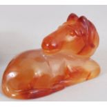 A 20TH CENTURY CHINESE CARVED AGATE STYLE MODEL OF A RECUMBENT HORSE, together with a wood stand,