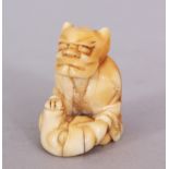 A JAPANESE MEIJI PERIOD IVORY NETSUKE OF A SEATED ONI, holding before him a Noh mask, 1.3in high.