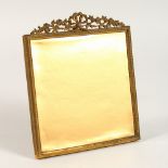 AN ORMOLU PICTURE FRAME, with ribbon and floral decoration. 7.5ins x 6.5ins.