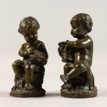 A SMALL PAIR OF BRONZE CUPIDS on marble bases. 5.5ins high.