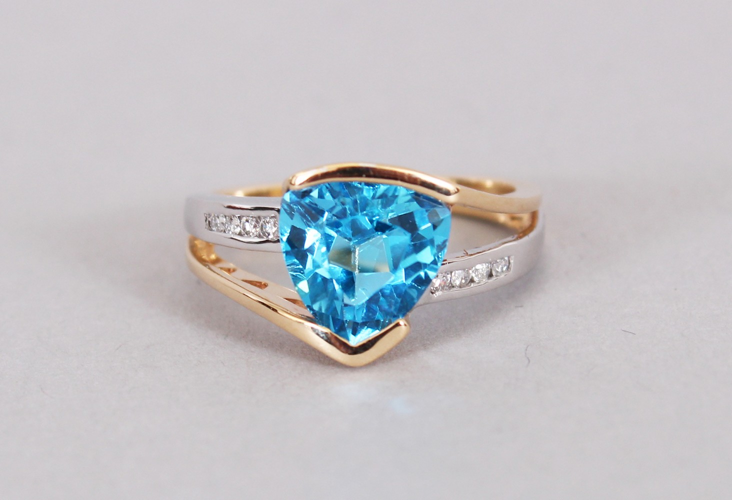 A 14CT WHITE AND YELLOW GOLD TWO TONE RING set with as trillion cut blue topaz approx. 3.23cts.